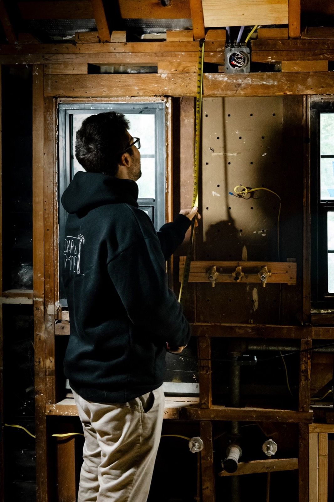 Daniel Muller measuring exposed framing on a Cedar and Stone jobsite