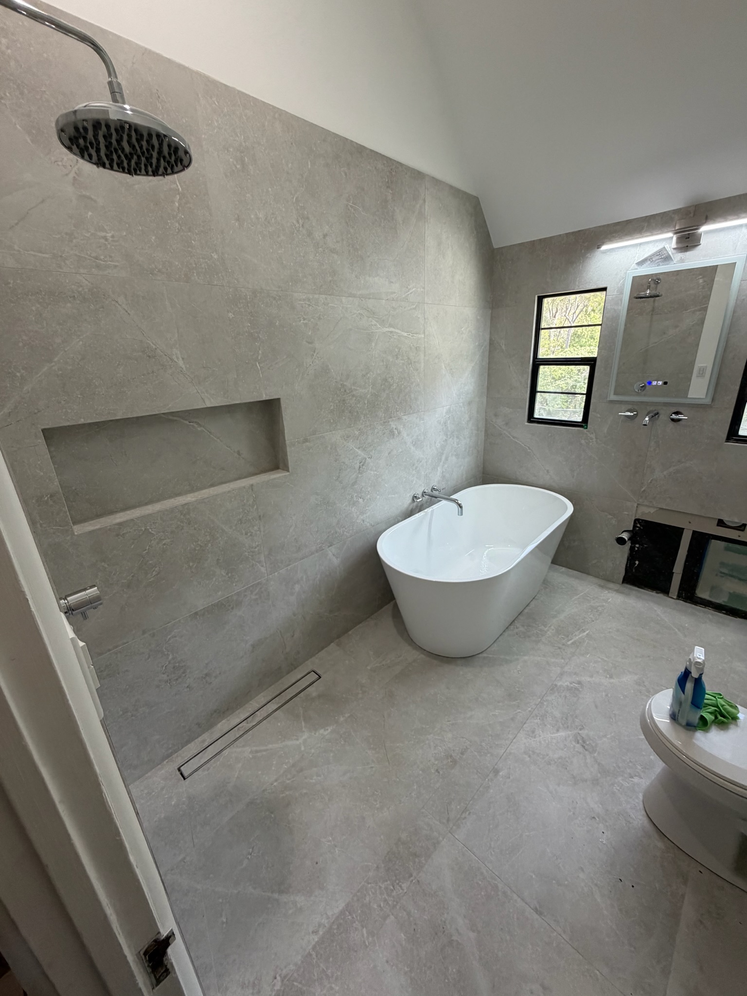Bathroom with large-format stone tile, shower, and freestanding tub