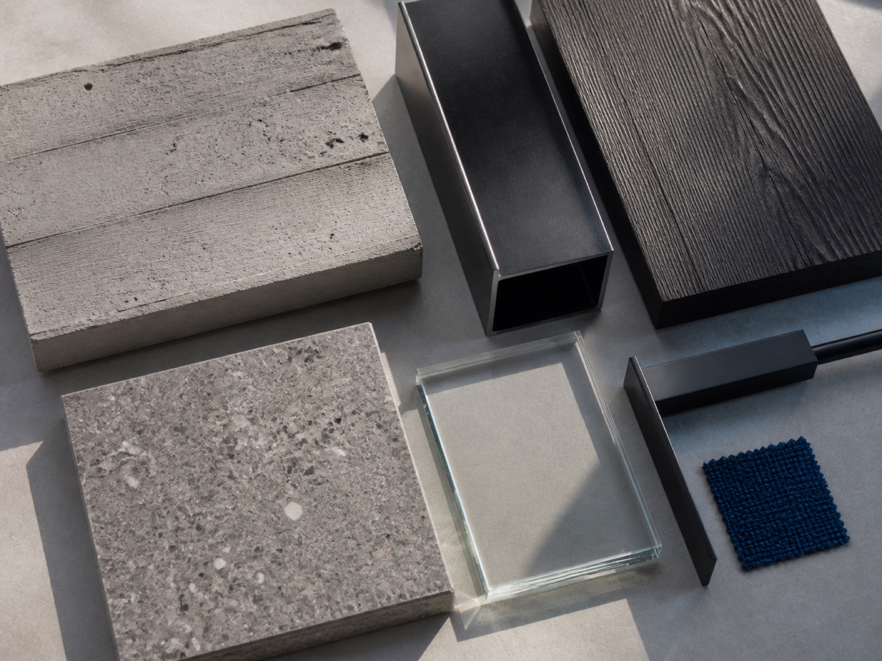 Concrete, terrazzo, blackened steel, charcoal wood, glass, and blue textile material study matching Rendering 03